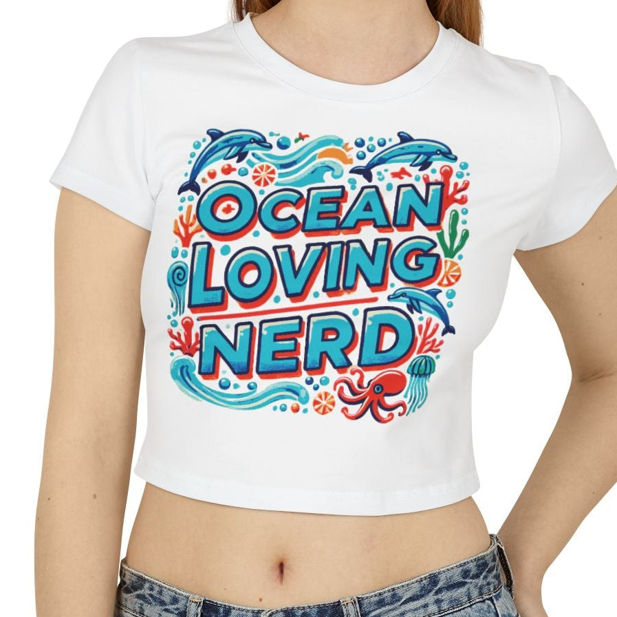 Model wearing 'Ocean Loving Nerd' in bold lettering with ocean animals on a Baby Tee - White