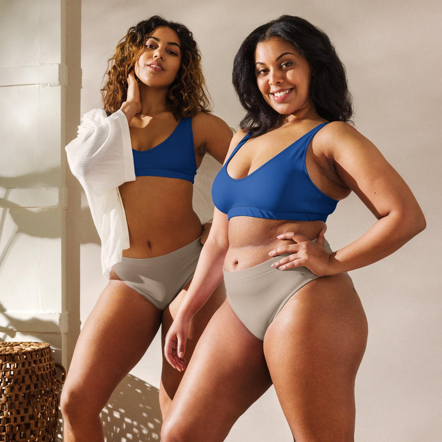 May include: Two women wearing matching underwear and tops. The underwear is a light brown color and the tops are a blue color. The women are standing next to each other and smiling at the camera.